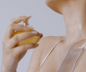Kobieta rozpylająca perfumy na szyję i dekolt.